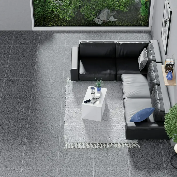 Feinsteinzeugfliese Recon - 60 x 60 cm, Schwarz, Matt - Draufsicht auf ein Wohnzimmer mit einem schwarzen Ecksofa, einem weißen Couchtisch und einem hellen Teppich. Eine moderne und stilvolle Einrichtung.