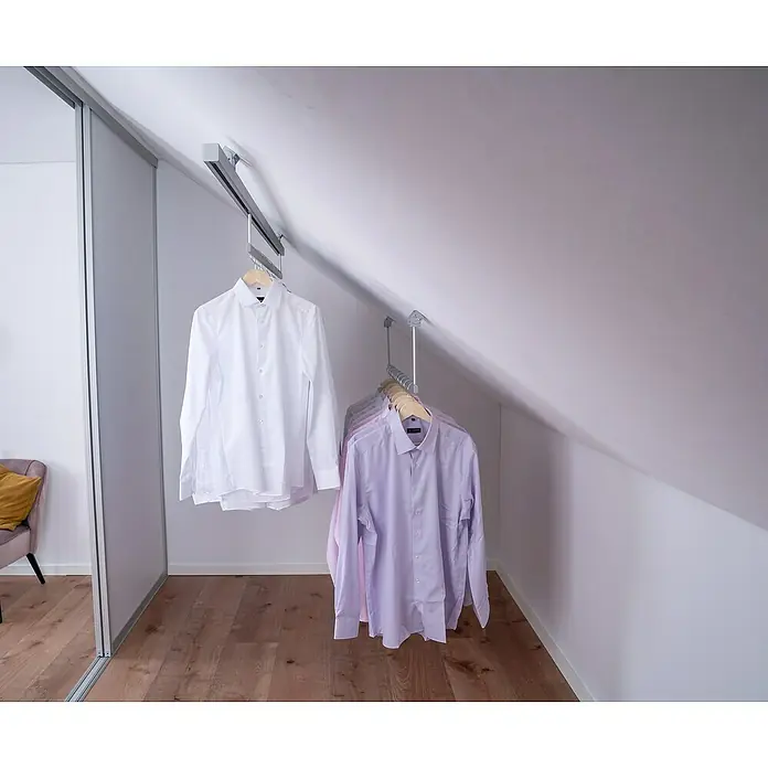 Room Plaza Easy Doing Kleiderstange - Passend für: Room Plaza Easy Doing Schiebetür-Bau-Sets, 1.000 mm, Fahrbar - Eine stilvolle Dachboden-Garderobenlösung mit einem ausziehbaren Kleiderlift, der weiße und lila Hemden ordentlich aufhängt und zusätzlichen Stauraum schafft.