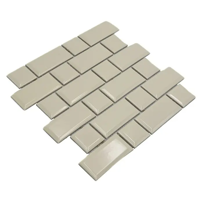 Mosaikfliese Metro Uni CG M10IM - 29,4 x 29,1 cm, Elfenbein, Glänzend - Nahaufnahme von beigefarbenen, rechteckigen Keramikfliesen, die in einem versetzten Muster angeordnet sind und eine glänzende Oberfläche haben.