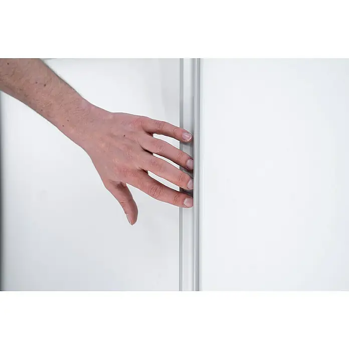 Room Plaza Easy Doing Schiebetür-Bau-Set KniestockReinweiß Miniperl, Profilfarbe: Silber - Eine Hand öffnet einen minimalistischen, modernen Kleiderschrank mit weißen Schiebetüren und schlichtem, silberfarbenem Rahmen.