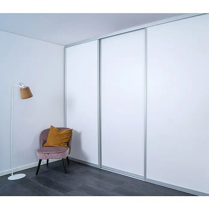 Room Plaza Easy Doing Schiebetür-Bau-Set - Signalweiß, Farbe Beschlag: Silber - Minimalistisch eingerichtetes Zimmer mit einem großen weißen Schiebetürenschrank, einem rosa Sessel und einer Stehlampe.