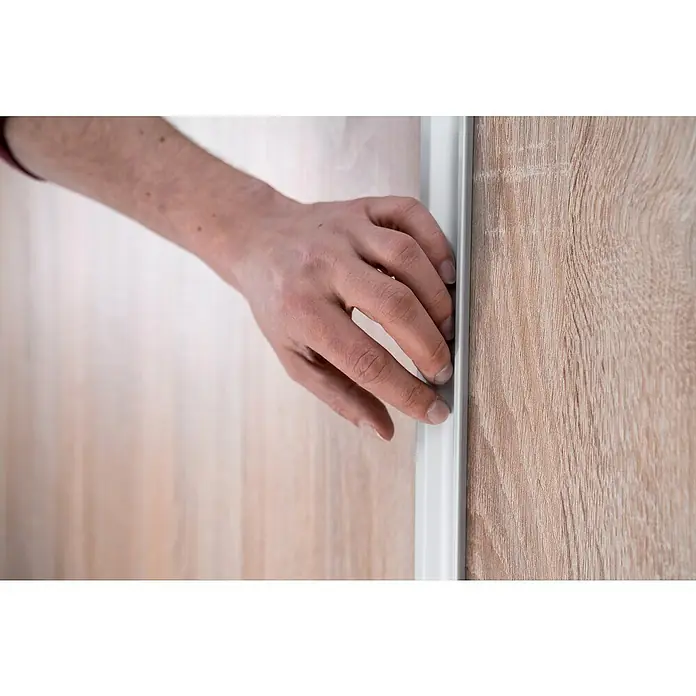 Room Plaza Easy Doing Schiebetür-Bau-Set KniestockBuche Naturwuchs, Profilfarbe: Silber - Ein Mann öffnet oder schließt eine Holztür mit einem silbernen Türgriff, wobei seine Hand den Fokus bildet.