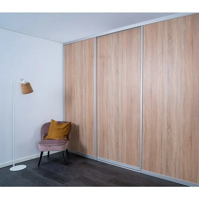 Room Plaza Easy Doing Schiebetür-Bau-Set - Eiche geplankt, Farbe Beschlag: Silber - Dreitüriger Schiebetürenschrank aus hellem Holz mit silbernen Akzenten in einem modernen Raum.