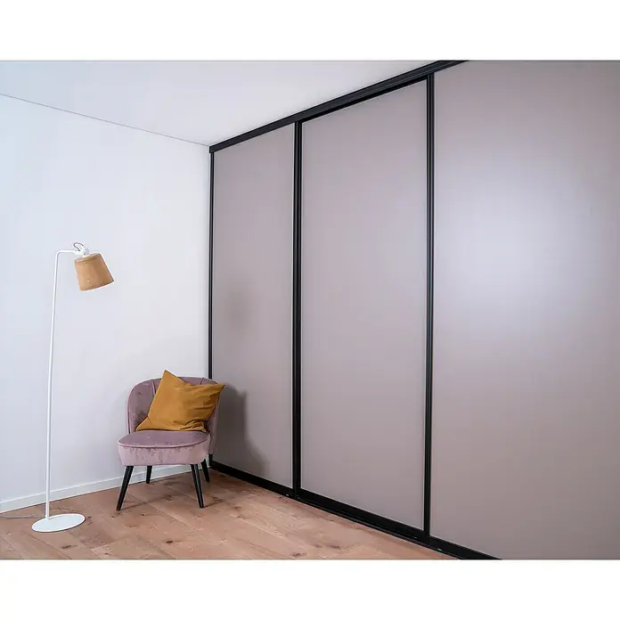 Room Plaza Easy Doing Schiebetür-Bau-Set - Taupe, Farbe Beschlag: Schwarz - Ein minimalistischer Raum mit einem Kleiderschrank mit Schiebetüren, einem lilafarbenen Sessel mit Kissen und einer Stehlampe.