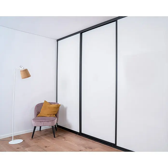 Room Plaza Easy Doing Schiebetür-Bau-Set - Hochglanz Schwarz/Hochglanz Weiß, Farbe Beschlag: Schwarz - Elegantes Zimmer mit großem, weißem Schiebetürenschrank, stilvollem Sessel und Stehlampe. Der Schrank bietet viel Stauraum.