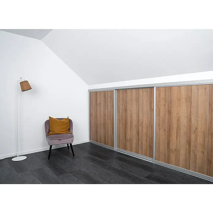 Room Plaza Easy Doing Schiebetür-Bau-Set Kniestock - Eiche Country, Farbe Beschlag: Silber - Ein modernes Zimmer mit einem Kleiderschrank mit Schiebetüren in Holzoptik, einem Sessel und einer Stehlampe für eine stilvolle Atmosphäre.