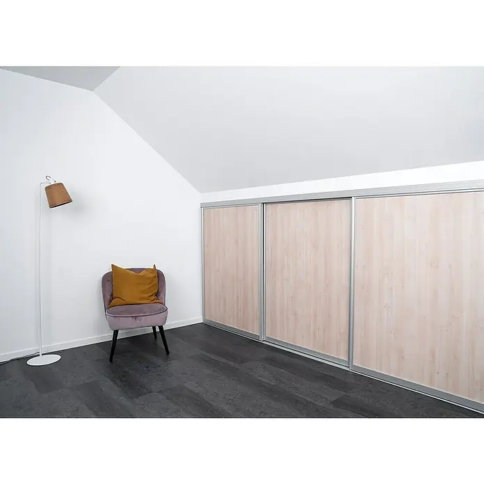 Room Plaza Easy Doing Schiebetür-Bau-Set Kniestock - Ahorn Naturwuchs, Farbe Beschlag: Silber - Ein helles, modernes Zimmer mit einem dreitürigen Schiebetürenschrank, einem Sessel und einer Stehlampe. Das Zimmer hat eine gemütliche Atmosphäre.