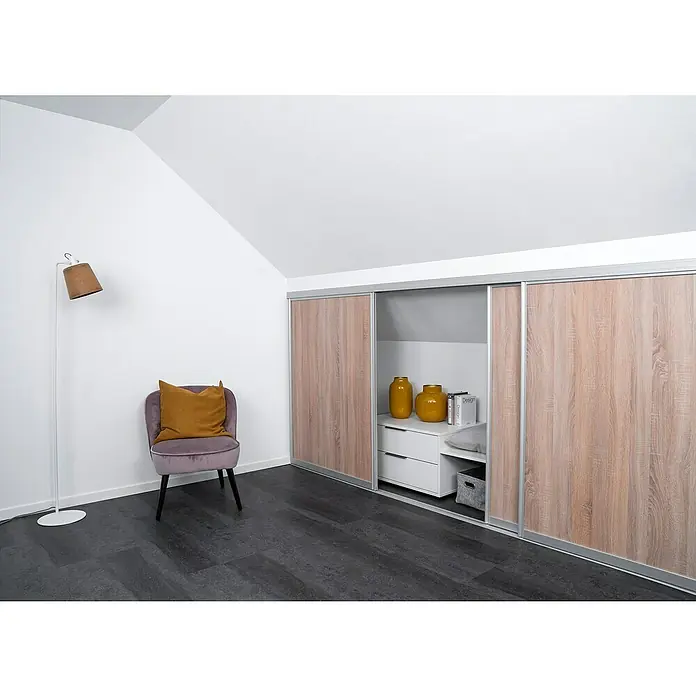 Room Plaza Easy Doing Schiebetür-Bau-Set Kniestock - Eiche geplankt, Farbe Beschlag: Silber - Attraktives Zimmer mit einem Kleiderschrank mit Schiebetüren in Holzoptik, ergänzt durch einen Stuhl und eine Stehlampe.