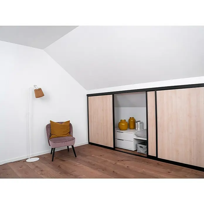 Room Plaza Easy Doing Schiebetür-Bau-Set KniestockAhorn Naturwuchs, Profilfarbe: Schwarz - Attraktives Interieur mit einem modernen Kleiderschrank mit Schiebetüren, einem stilvollen Sessel und einer Stehlampe, die eine warme Atmosphäre erzeugen.