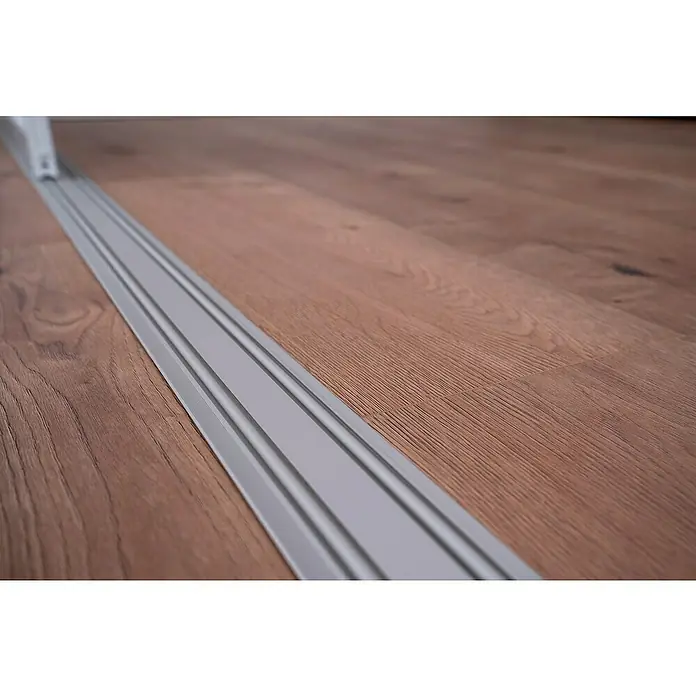 Room Plaza Easy Doing Schienen-Bau-SetPassend für: Room Plaza Easy Doing Schiebetür-Bau-Sets, 3.000 mm, Silber - Nahaufnahme einer silberfarbenen Übergangsleiste zwischen zwei Holzböden, die einen sauberen und modernen Übergang gewährleistet.