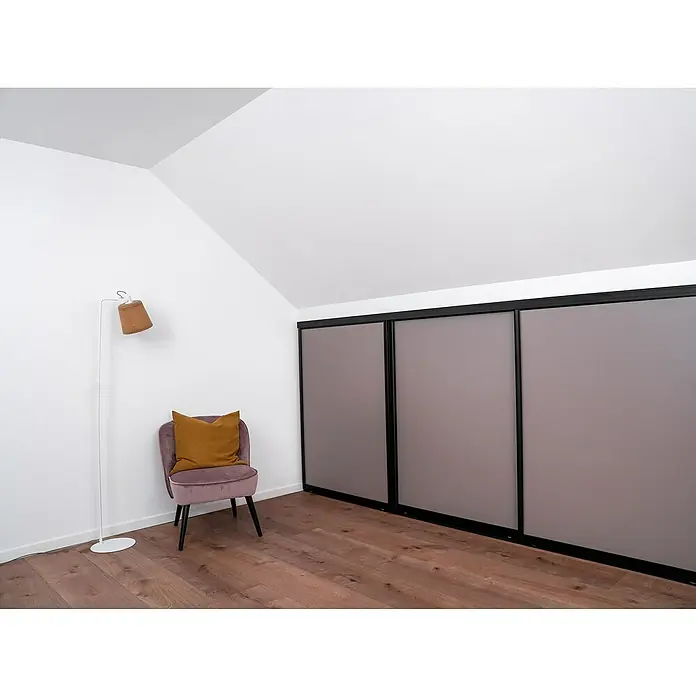 Room Plaza Easy Doing Schiebetür-Bau-Set Kniestock - Taupe, Farbe Beschlag: Schwarz - Einrichtung mit lilafarbenem Sessel, Stehlampe und einem Schrank mit drei grauen Schiebetüren in einem Dachzimmer.