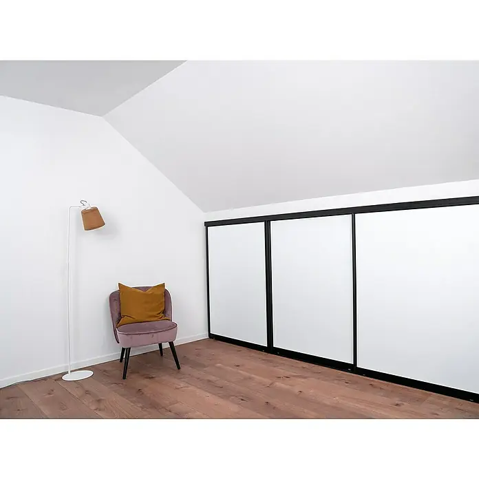 Room Plaza Easy Doing Schiebetür-Bau-Set KniestockSignalweiß, Profilfarbe: Schwarz - Schlafzimmer mit Einbauschrank mit weißen Schiebetüren, einem rosa Sessel und einer Stehlampe.