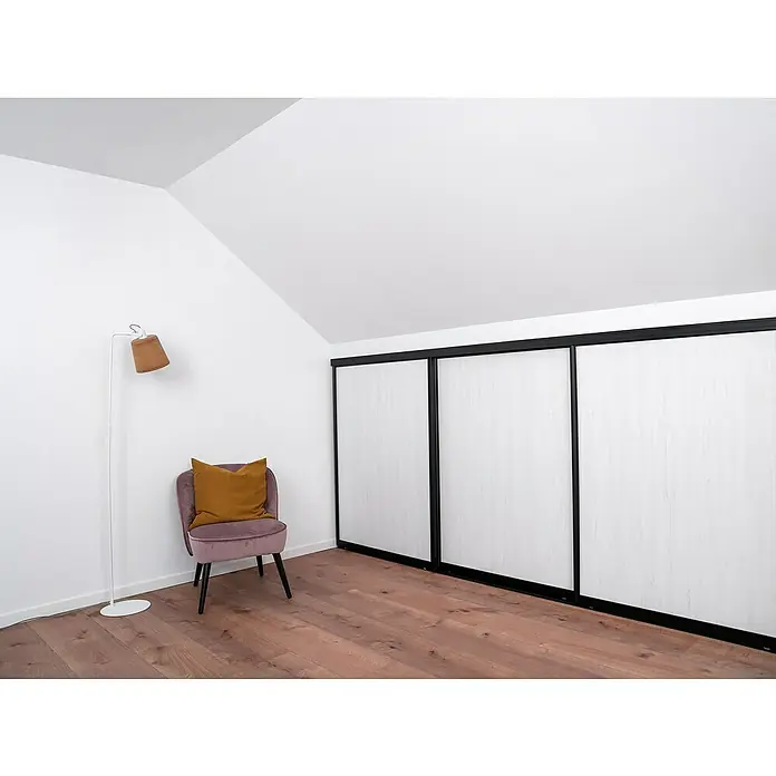 Room Plaza Easy Doing Schiebetür-Bau-Set Kniestock - Pinie weiß, Farbe Beschlag: Schwarz - Zimmer mit Schrankwand, Sessel und Stehlampe. Der Sessel hat einen Samtbezug und ein gelbes Kissen. Die Schrankwand ist weiß mit schwarzen Rahmen.