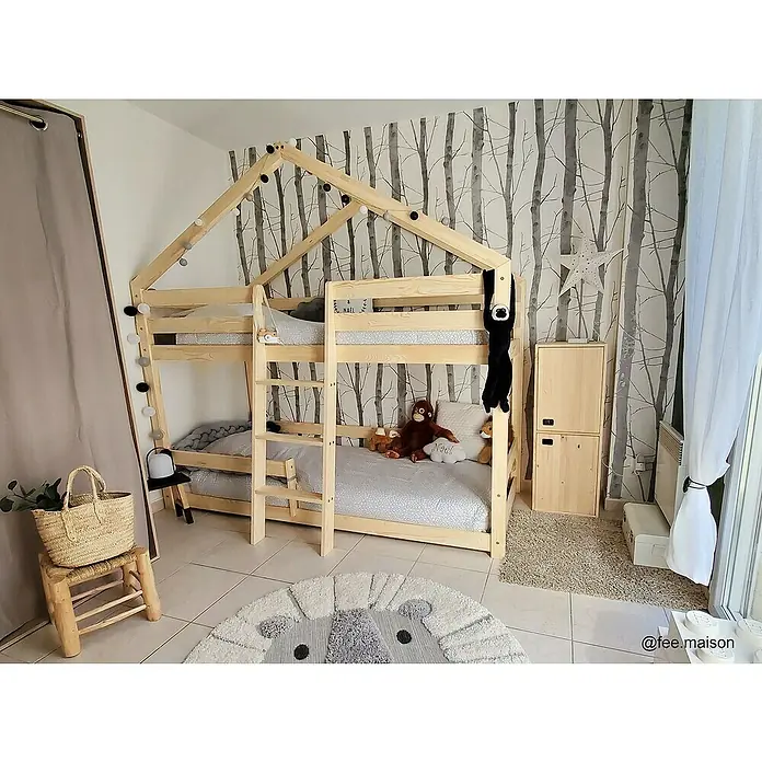 Astigarraga Dinamic Schrank - L x B x H: 33 x 37,3 x 105,4 cm, Kiefernholz - Kinderzimmer mit hellem Holzbett, dekoriert mit Lichtern und Stofftieren, auf einem gemusterten Teppich.