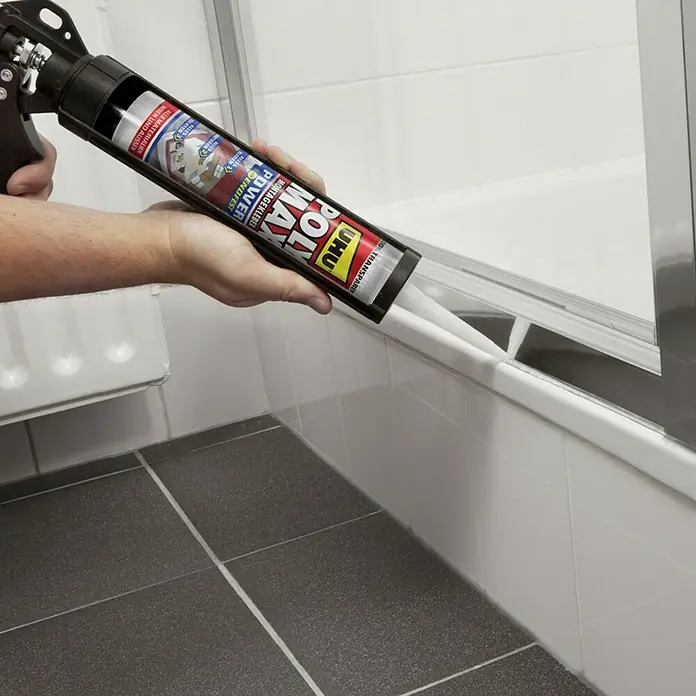UHU Poly Max Montagekleber Power - Transparent, 300 g, Kartusche - Ein Arbeiter verwendet eine Kartuschenpistole mit UHU Poly Max Power Kleber, um eine Badewanne abzudichten.