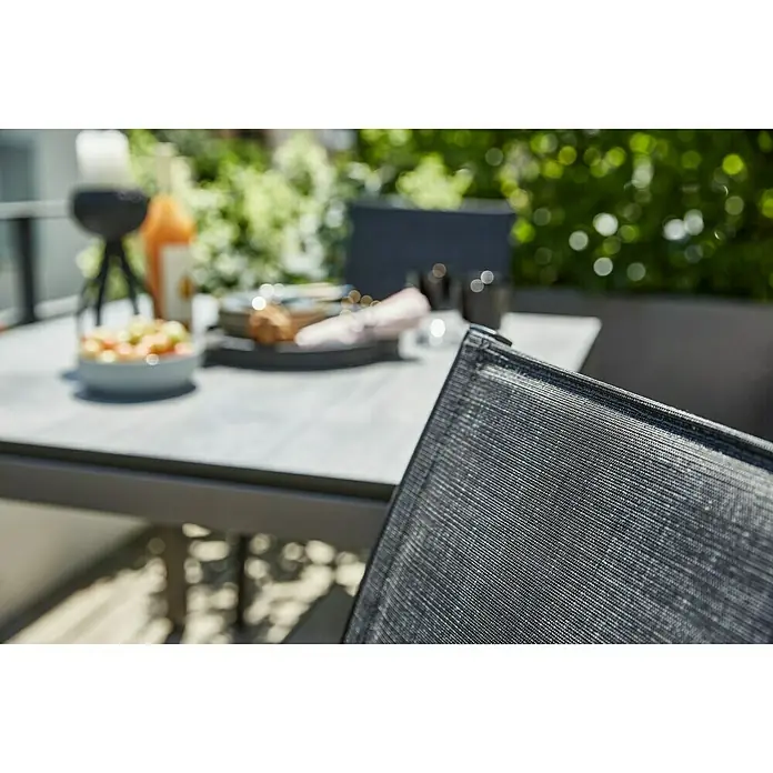 Sunfun Melina Gartensessel - Aluminium, Textilen, Stapelbar, Schwarz, B x T x H: 56,5 x 66 x 91 cm - Nahaufnahme eines Gartentisches mit Geschirr und einem Stuhl mit Textilbespannung.