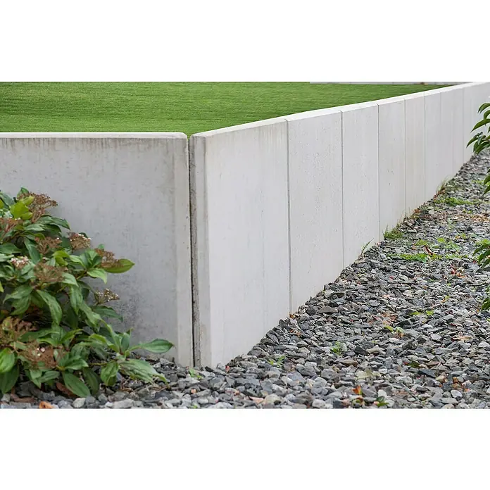Diephaus L-Stein InneneckeBewehrt, Höhe: 155 cm, Breite: 100 cm, Stärke: 12 cm, Grau - Eine moderne Gartenmauer aus Beton mit einem Kiesbeet davor und grüner Vegetation oben und an der Seite.