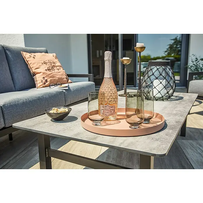 Sunfun Melina LoungetischL x B x H: 135 x 67 x 36 cm, Hochdruck-Schichtpressstoff (HPL), Schwarz - Ein rosa Pezzolato-Sekt, Gläser und Kerzen auf einem Tisch.