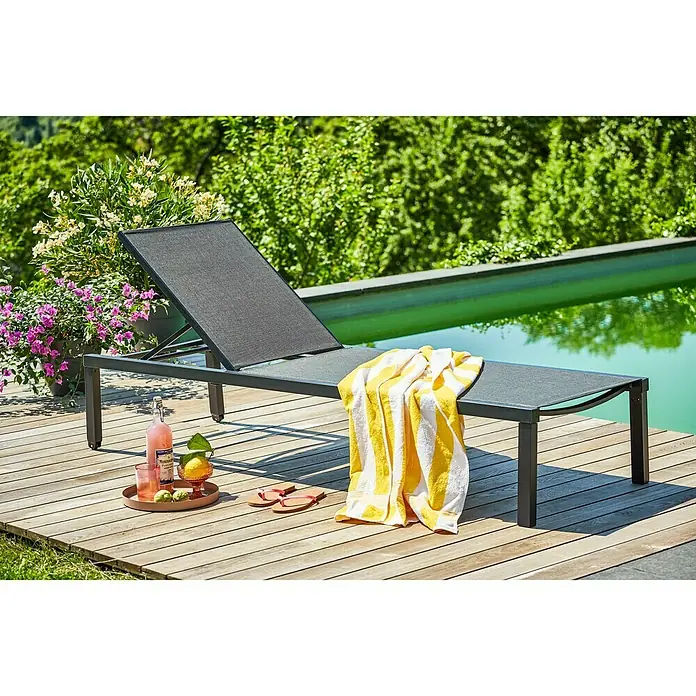 Sunfun Melina Liegenauflage - Grau, Polyester - Ein grauer Liegestuhl mit einem gelb-weiß gestreiften Handtuch und Getränken auf einer Holzterrasse.