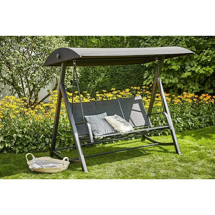 Sunfun Melina Hollywoodschaukel - B x T x H: 209 x 113 x 171 cm, Kunststoff, Schwarz - Eine graue Hollywoodschaukel mit Kissen und einem kleinen Korb auf einer grünen Wiese, umgeben von Blumen und Büschen.