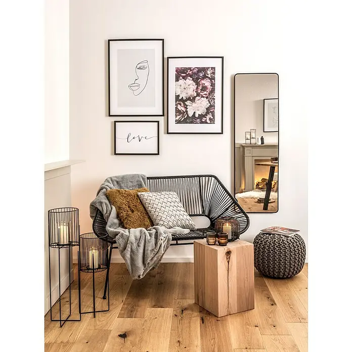 Bild - Love, B x H: 40 x 30 cm - Ein stilvolles Interieur mit einem schwarzen Rattansofa, dekoriert mit Kissen und einer weichen Decke, unter einer Galeriewand.