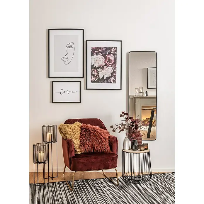 Stumpenkerze Safe - Ø x H: 7 x 10 cm, Wollweiß - Elegantes Wohnzimmer-Interieur mit einem burgunderroten Samtsessel, stilvollen Wandbildern und dekorativen Elementen wie Kerzenständern und Blumenarrangements.