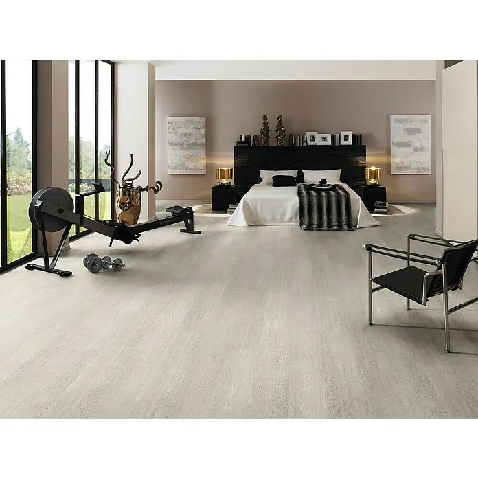 Laminat - Atlas Oak, Landhausdiele, 1.285 x 192 x 7 mm - Ein heller Raum mit einem Rudergerät und Hanteln. Das Schlafzimmer ist mit einem modernen Stuhl und einem grossen Bett ausgestattet.