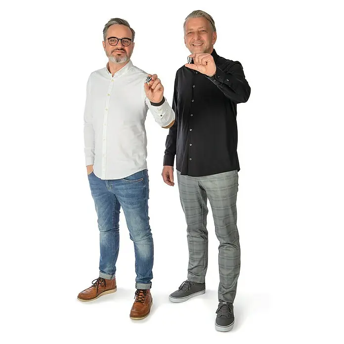 Puregreen Wassersparverschraubung - Geeignet für: Brausearmaturen, Chrom - Zwei Männer präsentieren ein kleines silbernes Produkt zwischen ihren Fingern, lässig gekleidet vor einem weißen Hintergrund.