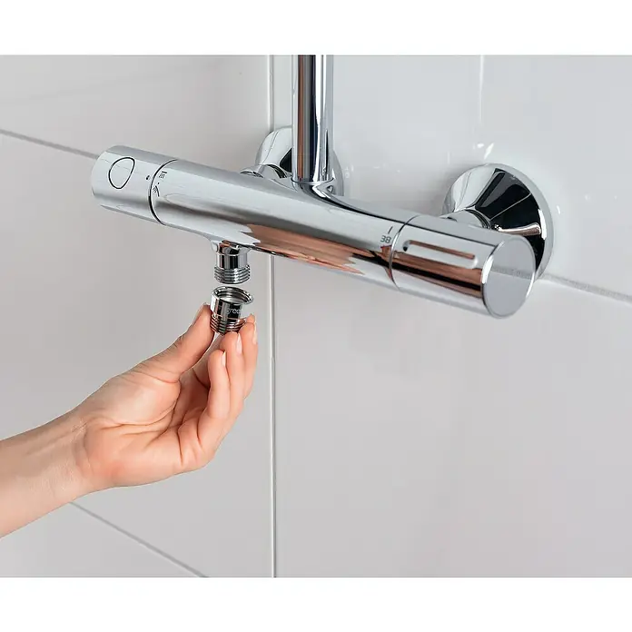 Puregreen Wassersparverschraubung - Geeignet für: Brausearmaturen, Chrom - Ein glänzender Duschkopf wird an einem verchromten Thermostat in einem Badezimmer mit weißen Fliesen befestigt.