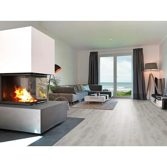 b!design Vinylbodenmuster SPC Sunny Pine - 280 x 160 x 3,8 mm, Landhausdiele - Wohnzimmer mit hellem Holzboden, modernem Kamin und Blick auf das Meer. Der Holzboden verleiht dem Raum eine warme und einladende Atmosphäre.