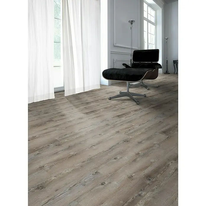 Fixed Vinylboden - Graukiefer, Landhausdiele, 1.219 x 184 x 2,5 mm - Ein stilvolles Interieur mit einem markanten Lounge-Sessel und einem eleganten Holzboden, der Wärme und Textur in den Raum bringt.