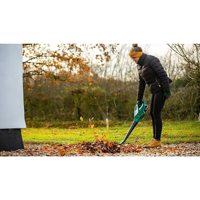 Bosch Power for All 18V Akku-Heckenscheren-Set EasyHedgeCut 18-45 + ALB 18 LI - 18 V, 2 Ah, Li-Ionen - Frau im Garten, die mit einem Laubbläser von Bosch das Laub zusammenbläst, um den Garten sauber und ordentlich zu halten.