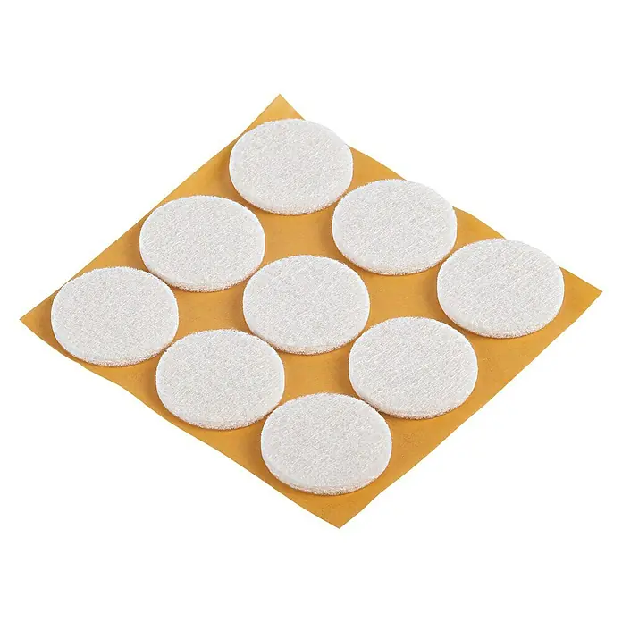 Suki Patín antideslizante para alfombras - Diámetro: 25 mm, Blanco, Pegado, 9 ud. - Primer plano de protectores de fieltro para muebles sobre un cartón cuadrado, sobre un fondo negro.