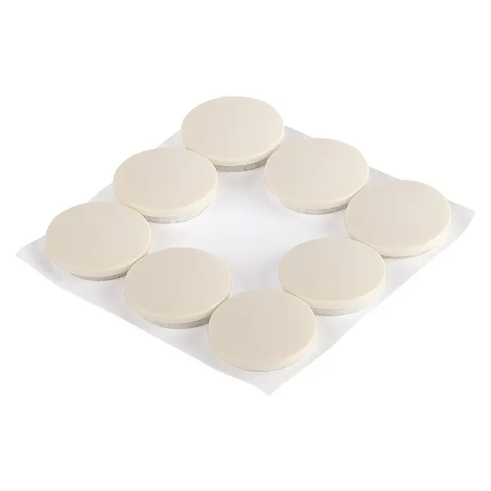 Fix-o-moll Teppichgleiter - Durchmesser: 22 mm - Nahaufnahme von einer Gruppe von runden, beigen Pads, die auf einem weißen quadratischen Tuch angeordnet sind.