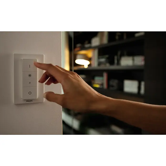 Philips Hue LED-Deckenstrahler RunnerL x B x H: 9 x 11 x 10,7 cm, 1 Stk. - Ein Philips Hue Dimmschalter an einer Wand, der von einer Hand bedient wird. Das elegante Design integriert sich nahtlos in moderne Wohnräume.