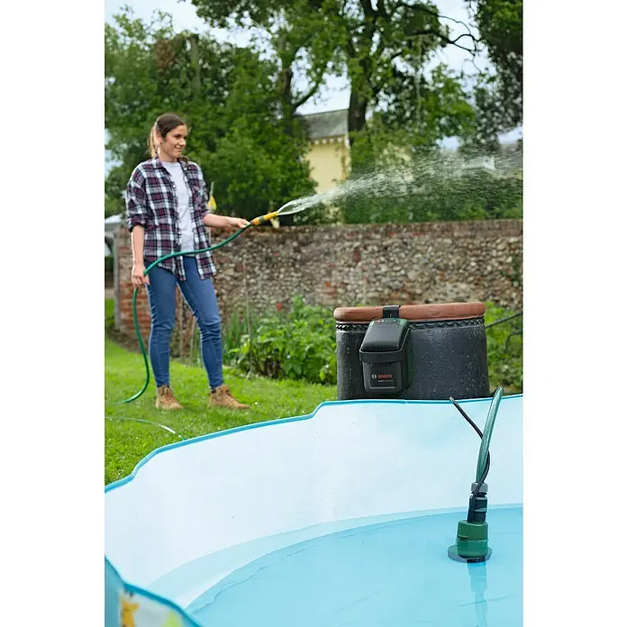 Bosch Power for All 18V Akku-Regenfasspumpe GardenPump 18V-2000 - 18 V, Ohne Akku, Max. Fördermenge: 2.000 l/h - Ein Bosch Gartenpumpe mit Akku wird in einem Garten verwendet, während eine Frau einen Pool mit einem Gartenschlauch befüllt.