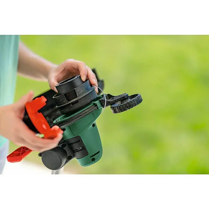 Bosch Power for All 18V Akku-Rasentrimmer UniversalGrassCut 18V-26 - 18 V, 2,5 Ah, 1 Akku - Nahaufnahme einer Person, die einen Rasentrimmer mit grünem Gehäuse und schwarzem Schneidkopf bedient.