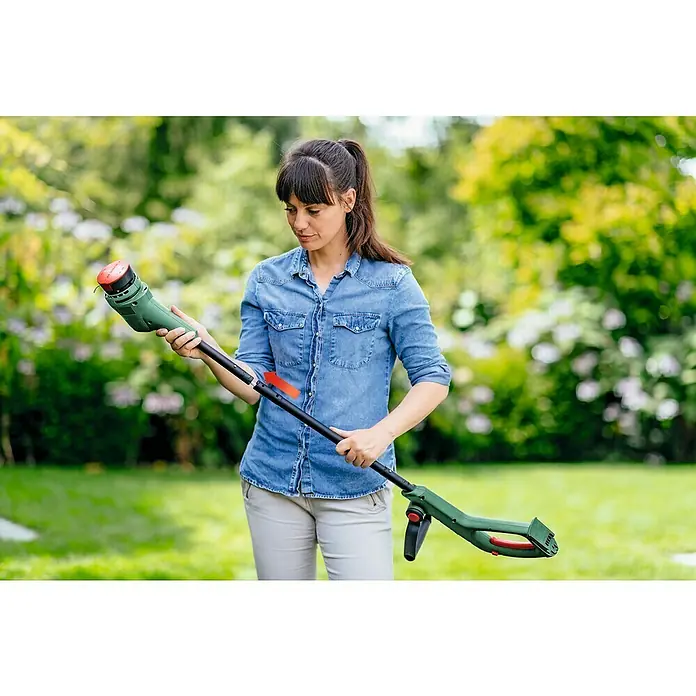 Bosch Power for All 18V Akku-Rasentrimmer EasyGrassCut 18V-260 - 18 V, 2 Ah, 2 Akkus - Eine Frau montiert einen grünen Bosch Rasentrimmer im Garten. Das Gerät hat einen Teleskopstiel und einen roten Spulenkopf.