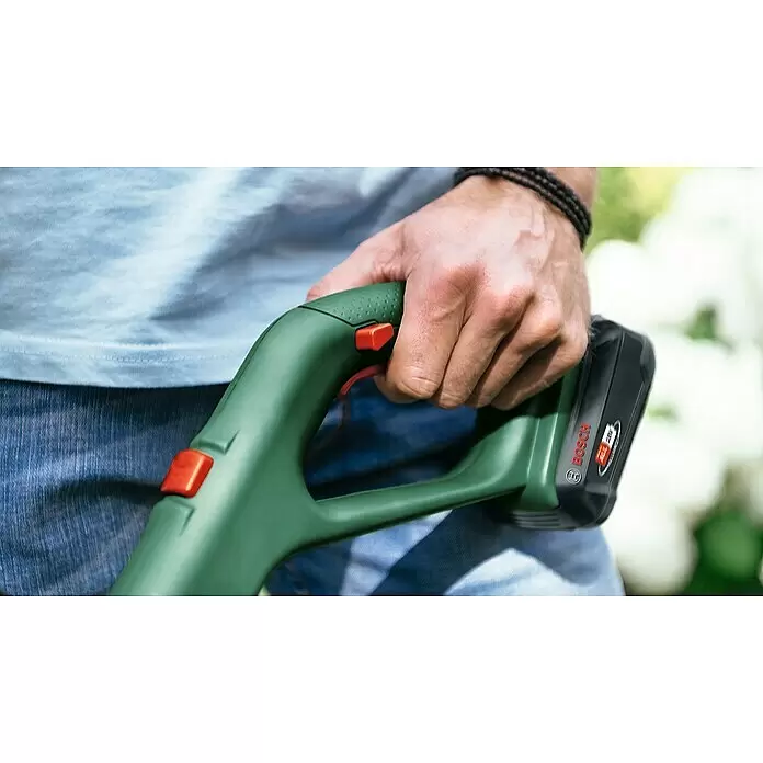 Bosch Power for All 18V Akku-Rasentrimmer EasyGrassCut 18V-260 - 18 V, 2 Ah, 2 Akkus - Person hält grünes Bosch Akku-Gartengerät mit schwarzem Akku und orangefarbenen Tasten.