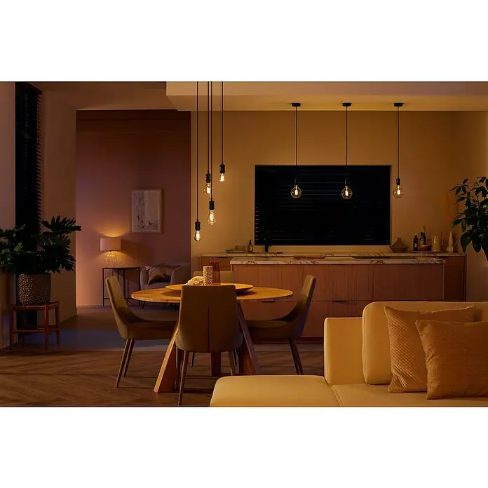 Philips Hue Smart-LED-Lampe White Ambiance FilamentE27, Dimmbar, Warmweiß, 550 lm, 7 W, Lampenbezeichnung: G125 - Einrichtung mit einem Esstisch und eleganten Pendelleuchten, die eine warme Atmosphäre schaffen.