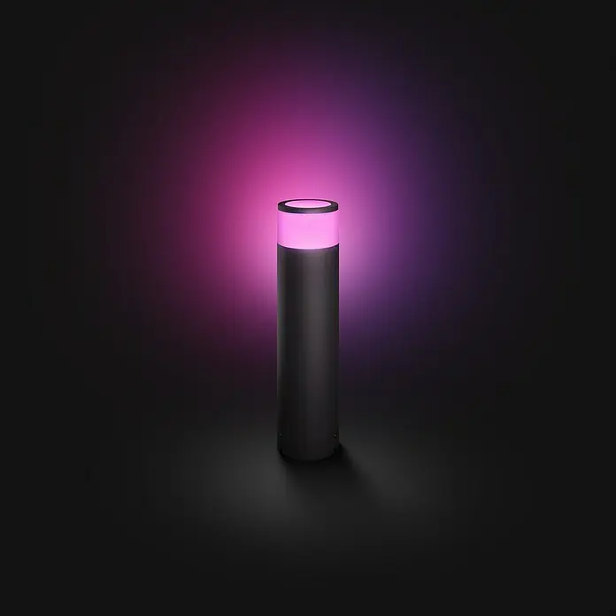 Philips Hue LED-Sockelleuchte Calla White & Color Ambiance8 W, Schwarz, Ø x H: 10,4 x 40 cm - Das Bild zeigt eine moderne, zylindrische Tischleuchte, die in einem dunklen Raum in einem auffälligen Pink leuchtet und einen modernen Akzent setzt.