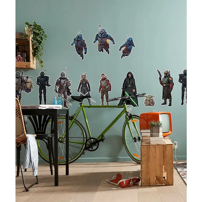 Komar Star Wars Wandtattoo Mandalorian Iconic Figures - Bunt, 70 x 100 cm, 12 -tlg. - Ein grünes Fahrrad lehnt an einer Wand mit Star Wars-Aufklebern, ein Fernseher steht daneben.