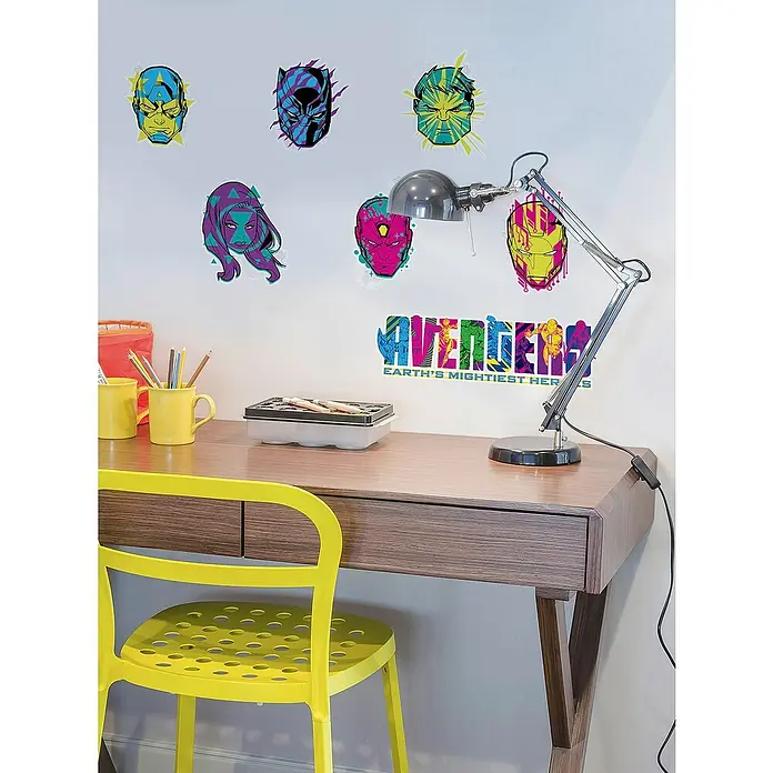 Komar Marvel Wandtattoo Avengers Mightiest Heroes - Bunt, 70 x 100 cm, 7 -tlg. - Ein hölzerner Schreibtisch mit einem gelben Stuhl und einer silbernen Schreibtischlampe, dekoriert mit Avengers-Wandaufklebern.