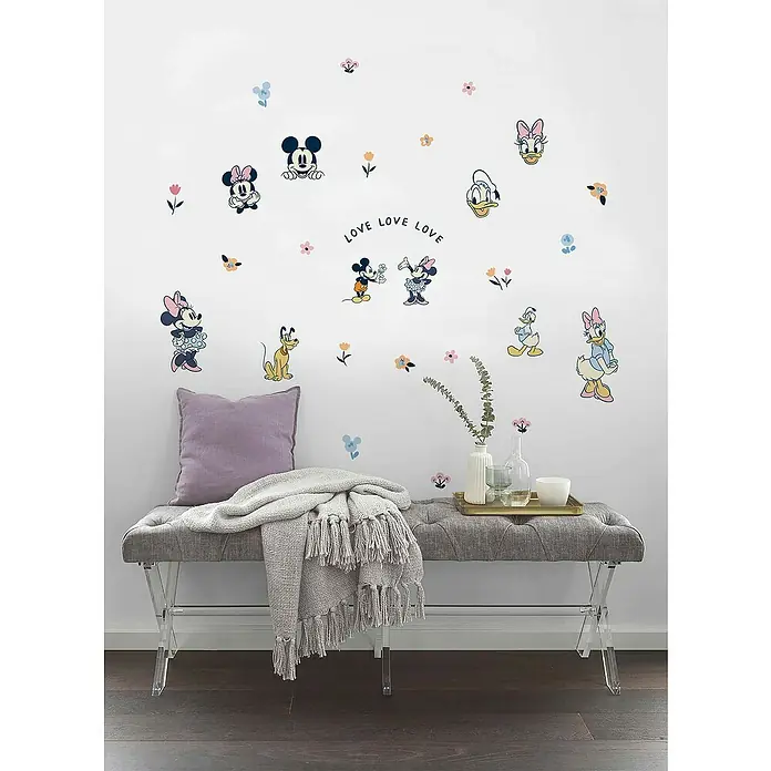 Komar Wandtattoo Love, Love, Love Mickey Mouse - Bunt, 50 x 70 cm, 40 -tlg. - Eine stilvolle Bank mit grauer Polsterung und Acrylbeinen, dekoriert mit Disney-Wandstickern und sanften Textilien.