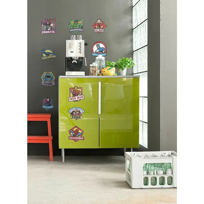 Komar Marvel Wandtattoo Avengers Classic Badges - Bunt, 50 x 70 cm, 10 -tlg. - Ein grüner Schrank mit Marvel-Aufklebern, einer Kaffeemaschine und Accessoires, die eine verspielte Küchenecke bilden.