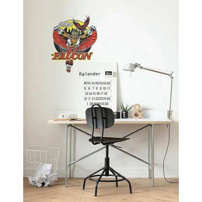 Komar Marvel Wandtattoo Falcon Comic Classic - Rot, 50 x 70 cm, 1 -tlg. - Ein Schreibtisch mit einem Stuhl, einer Lampe und einem Kalender mit einem Superhelden-Aufkleber an der Wand.