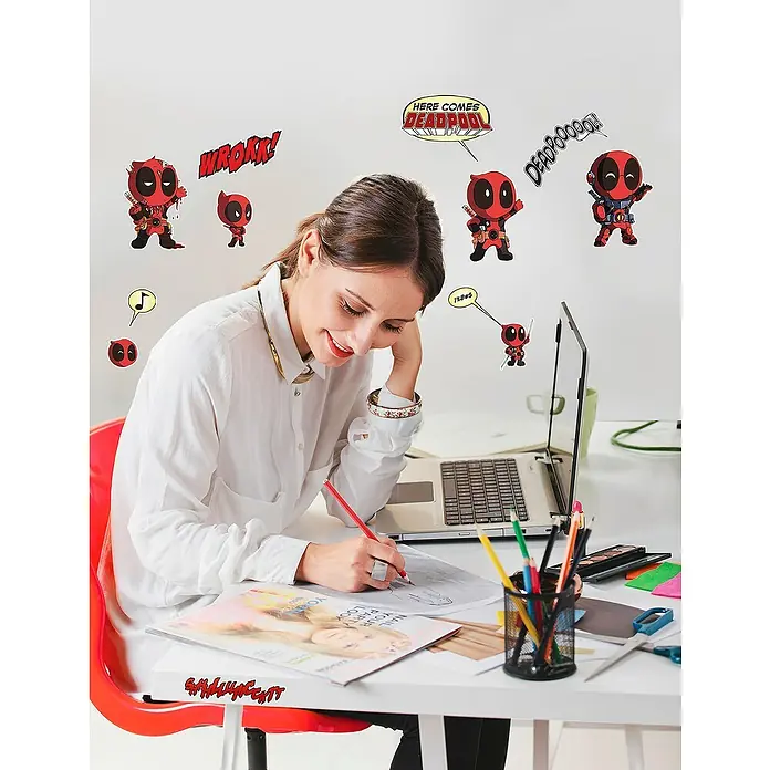 Komar Marvel Wandtattoo Deadpool Cute - Bunt, 50 x 70 cm, 12 -tlg. - Eine Frau am Schreibtisch, umgeben von Deadpool-Wandstickern, die eine kreative und spielerische Arbeitsatmosphäre schaffen.