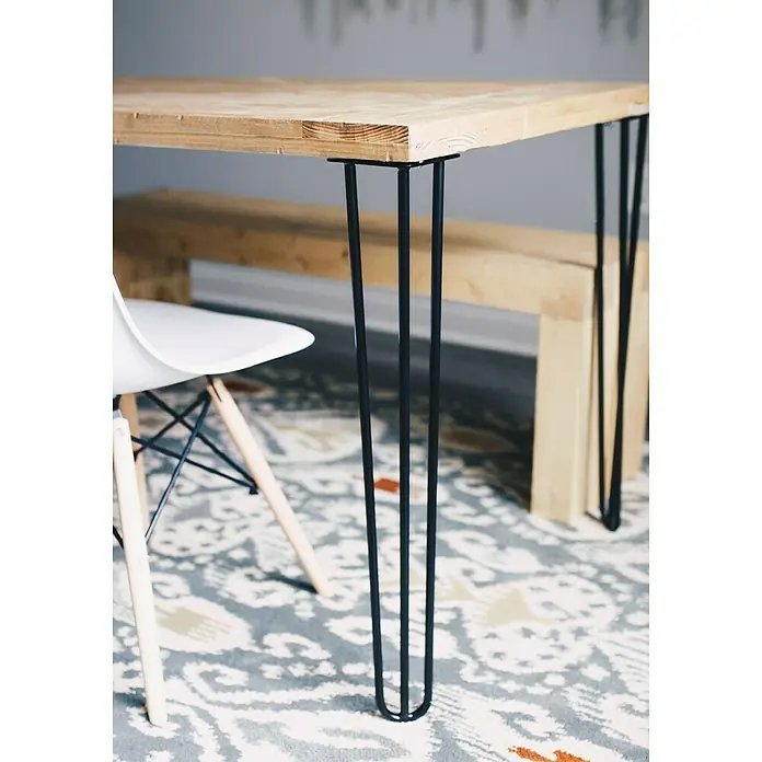 Rei Pata para muebles Tri - Ø x Al: 10 x 71 cm, Acero, Negro - Primer plano de una mesa de madera con patas negras, complementada con una alfombra con detalles estampados debajo.