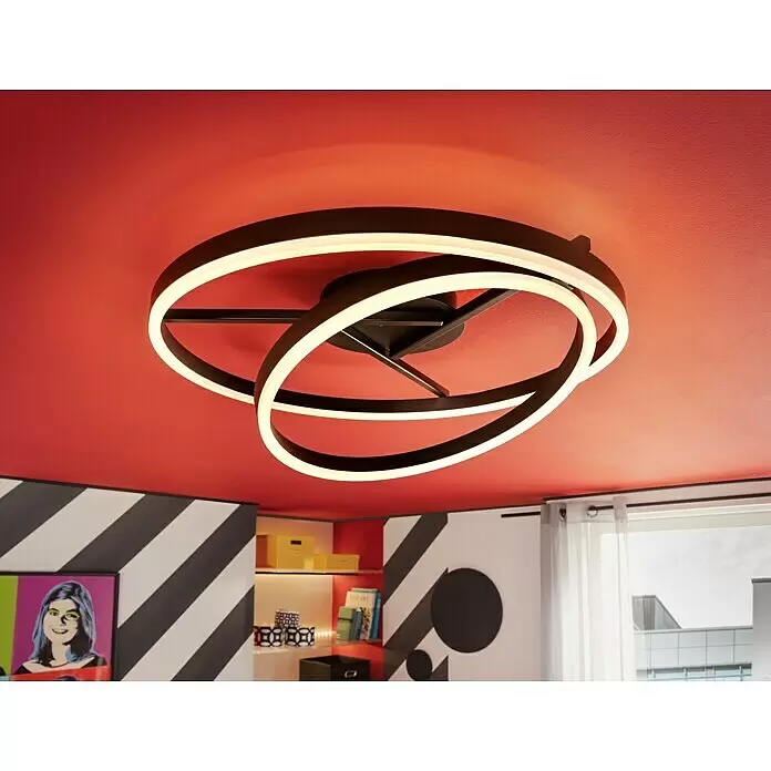 Tween Light LED-Deckenleuchte rund Two Rings - 40 W, Ø x H: 600 mm x 23 cm, Schwarz - Moderne schwarze LED-Deckenleuchte mit ineinander verschlungenen Ringen an einer roten Decke, die einen Raum beleuchtet.