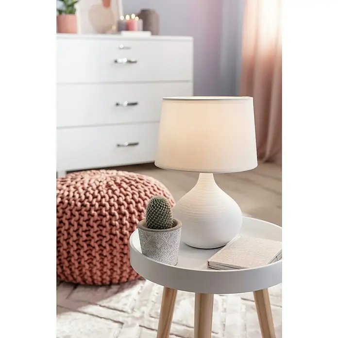 Trio Lighting Lámpara de sobremesa Martin - 40 W, L x An x Al: 20 x 20 x 29 cm, Blanco, E14 - Primer plano de una lámpara de noche con pantalla blanca junto a un cactus y un cuaderno en una mesa auxiliar.